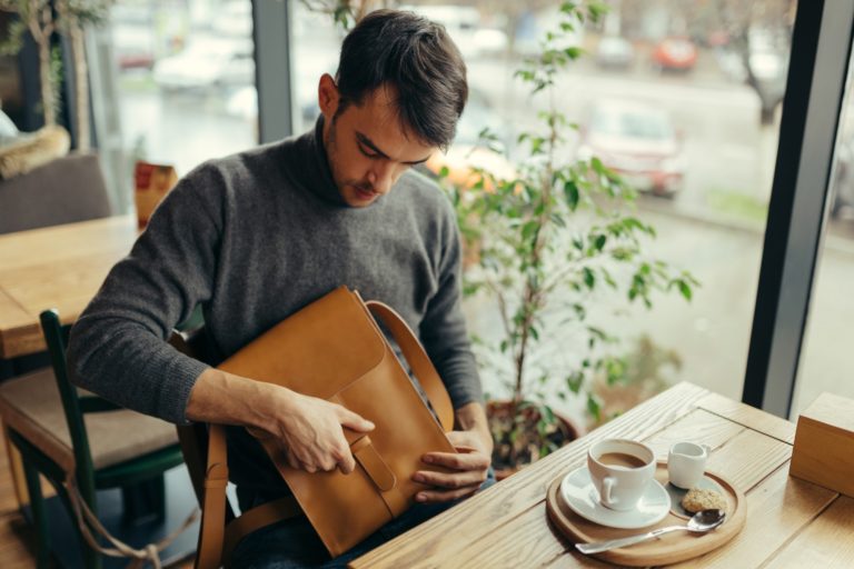 Handsome businessman with leather bag sitting at the table